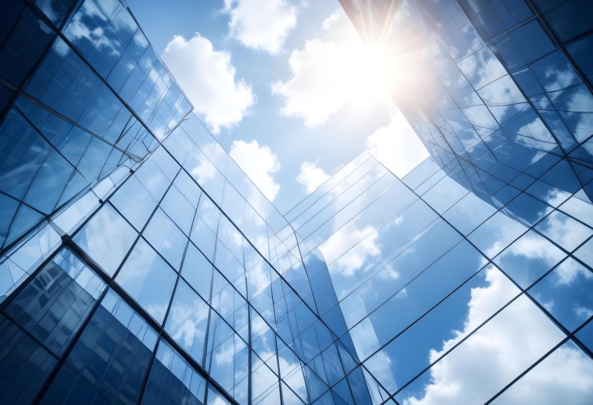 Low Angle Shot Of A Modern Glass Skyscraper Reflecting The Blue Sky And White Clouds Sun Shining Through The Clouds Creating A Bright And Airy Atmosphere 84 F369
