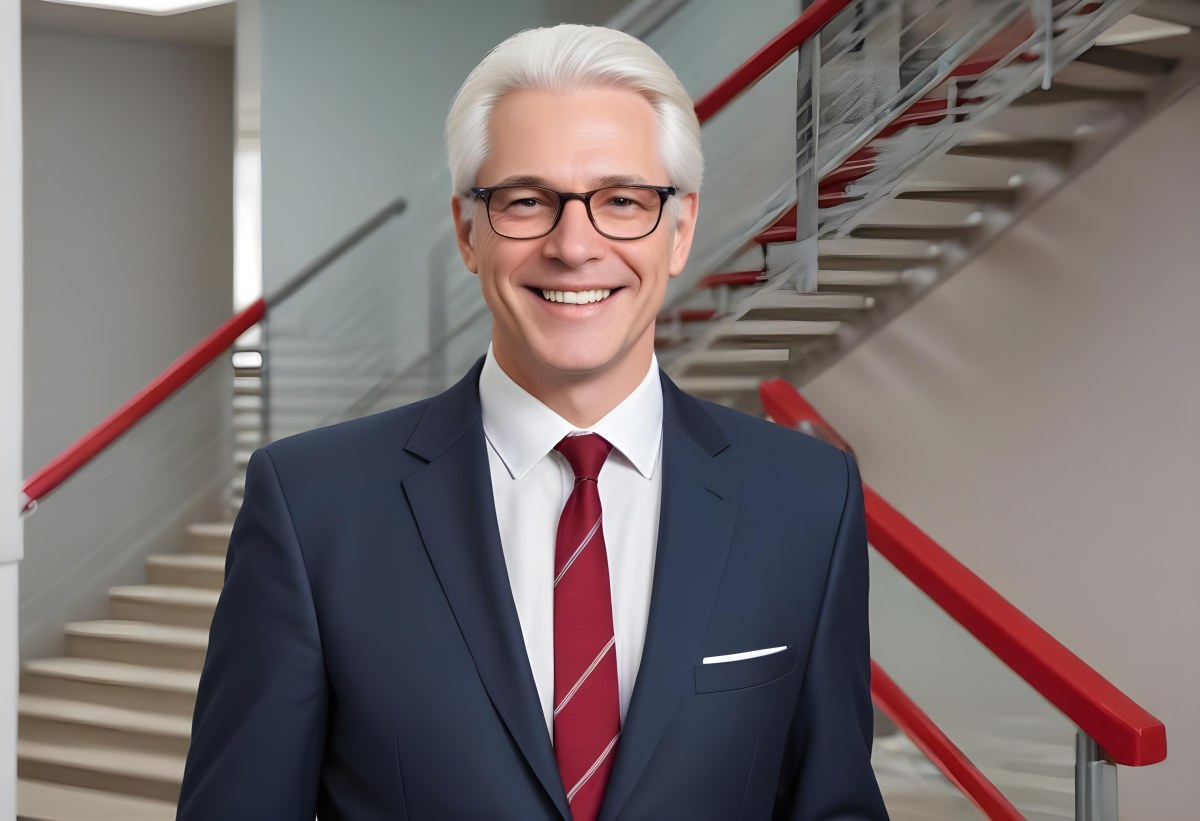 White Man 50 Years Old With White Hair And Glasses Wearing A Suit And A Red Tie Smiling In An Office Environment With A Staircase In The Background 15 7031