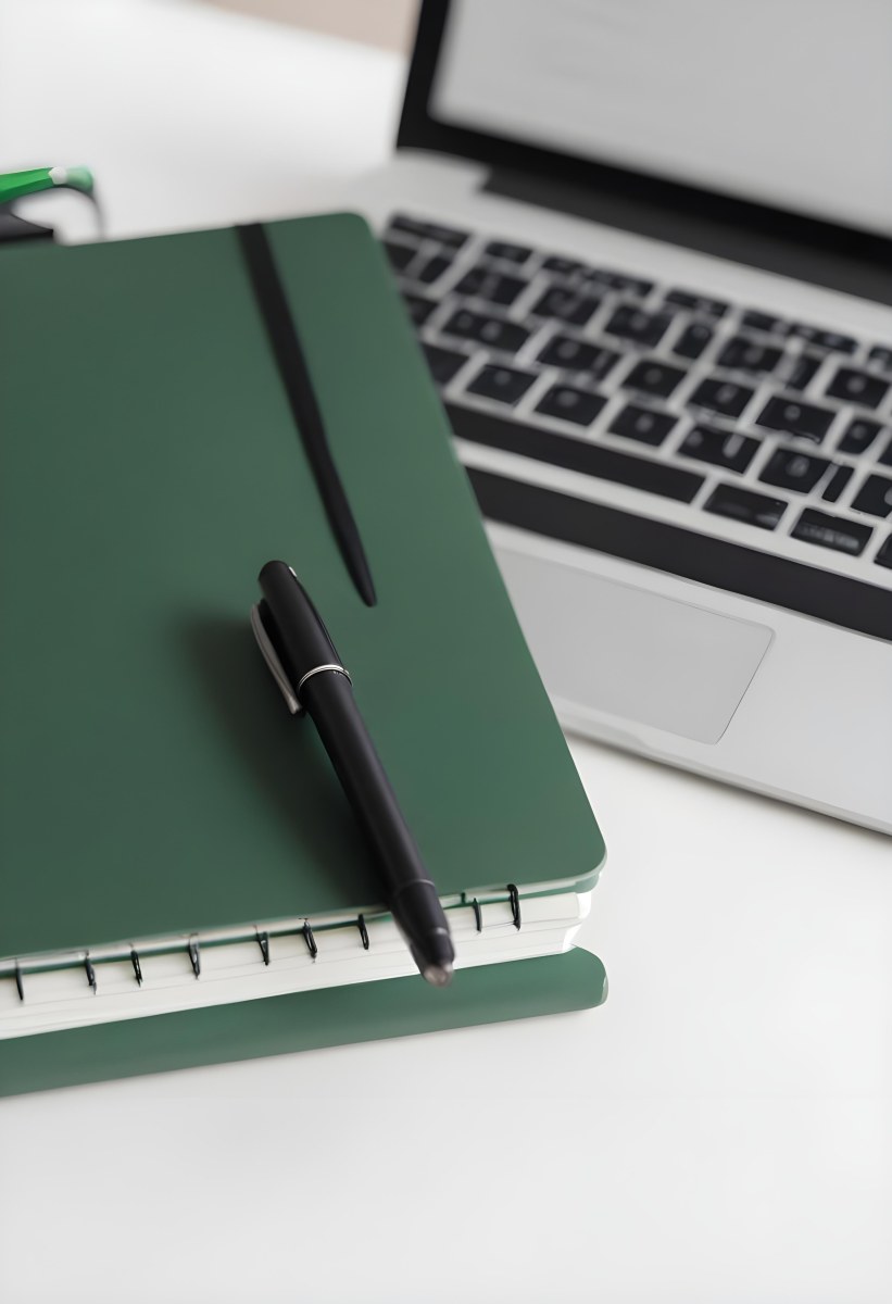 A Green Notebook With A Black Pen Next To A Laptop On A Desk In Daylight 4 97cd