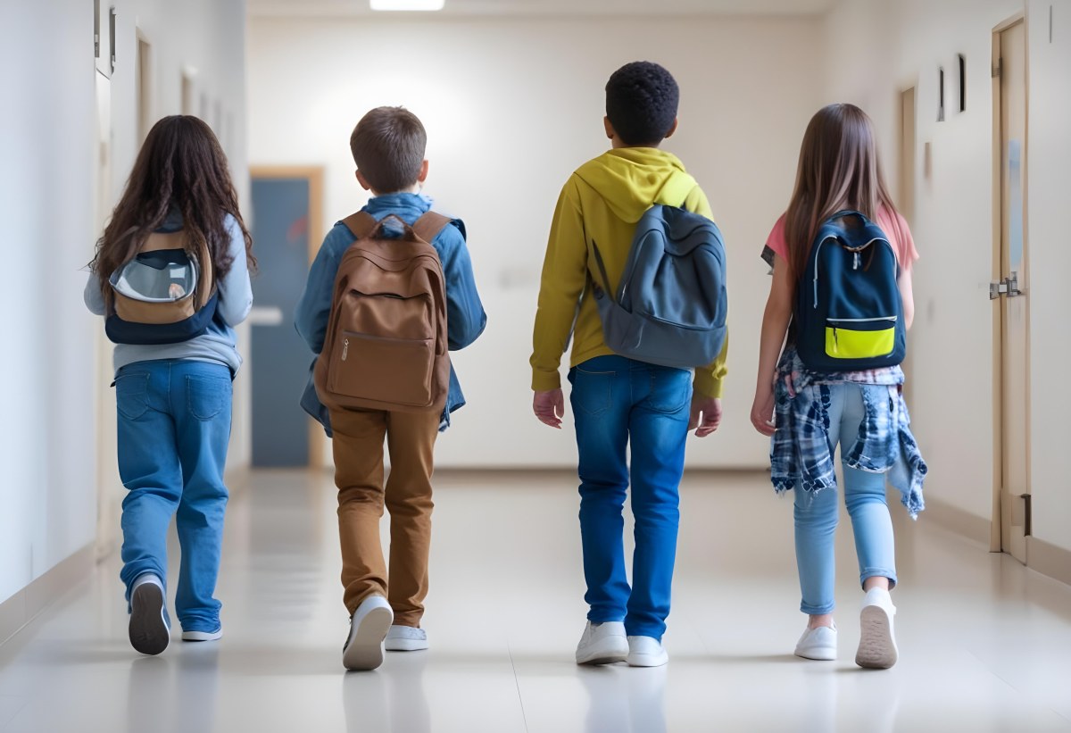 A Group Of Elementary School Students Walking Down A School Hallway Carrying Backpacks The Students Appear To Be A Mix Of Races With Both Boys And Girls And Are Wearing Casual Clothing Like Jeans And T Shirts 8 C77a
