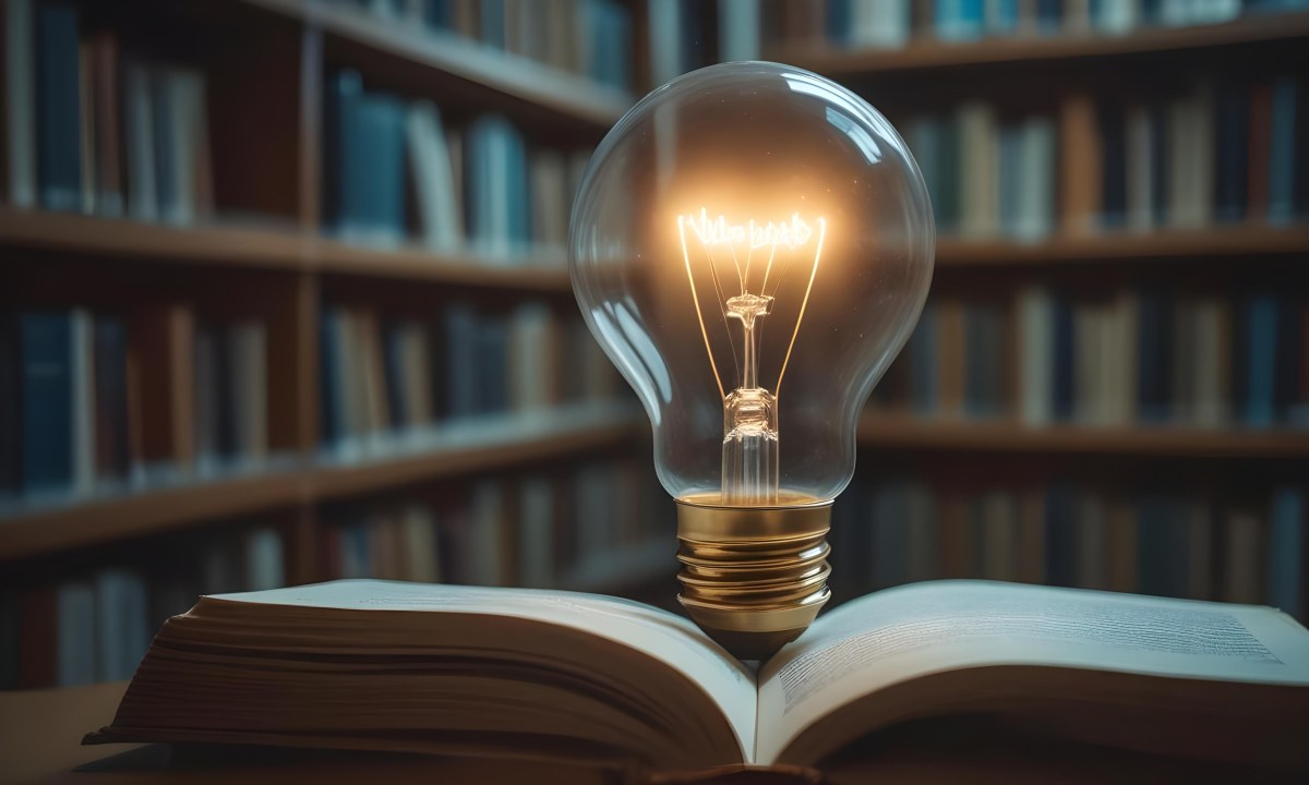 A Light Bulb On Top Of An Open Book Library In The Background With Many Books On The Shelves Warm Light Knowledge Concept 16 9dc3