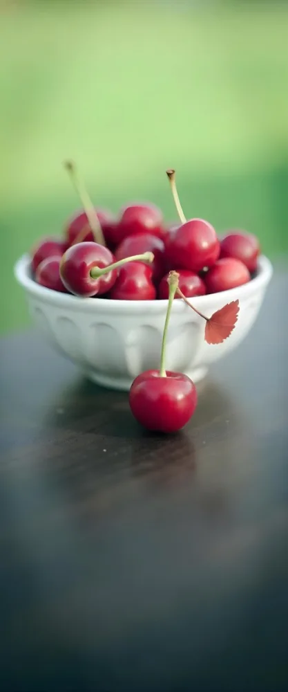 A Bowl Full Of Red Cherries With A Red Leaf On A Wooden Table With A Blurred Red Background 5 3db6