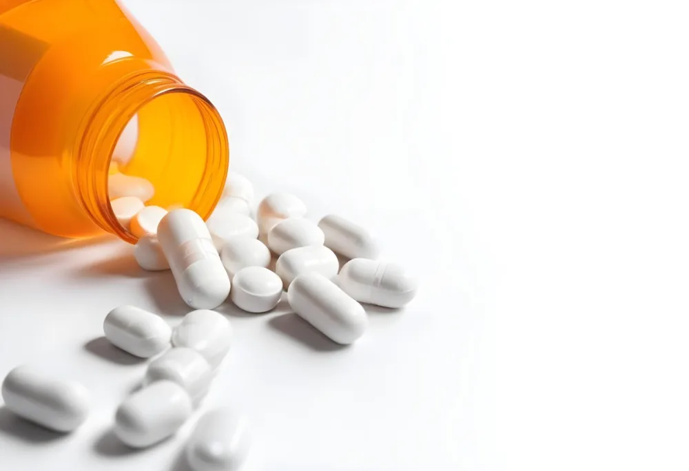 White Pills Spilling Out Of An Orange Pill Bottle On A White Surface Studio Shot 1 306b