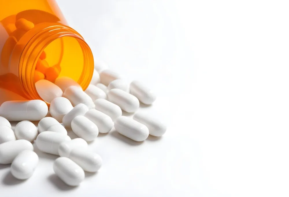 White Pills Spilling Out Of An Orange Pill Bottle On A White Surface Studio Shot 4 6cde