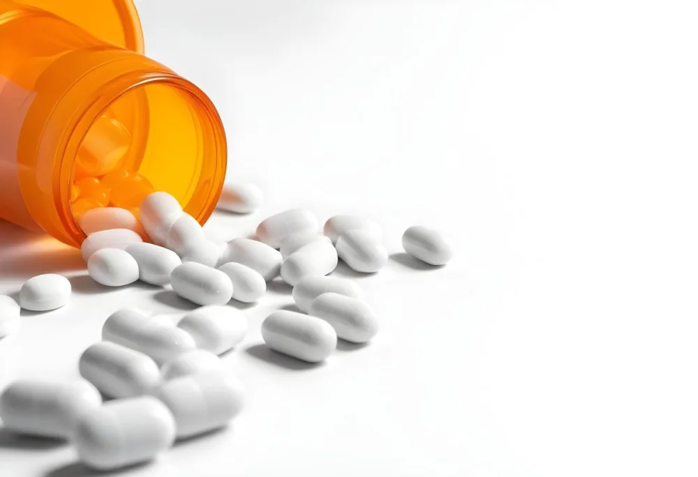 White Pills Spilling Out Of An Orange Pill Bottle On A White Surface Studio Shot 6 2829