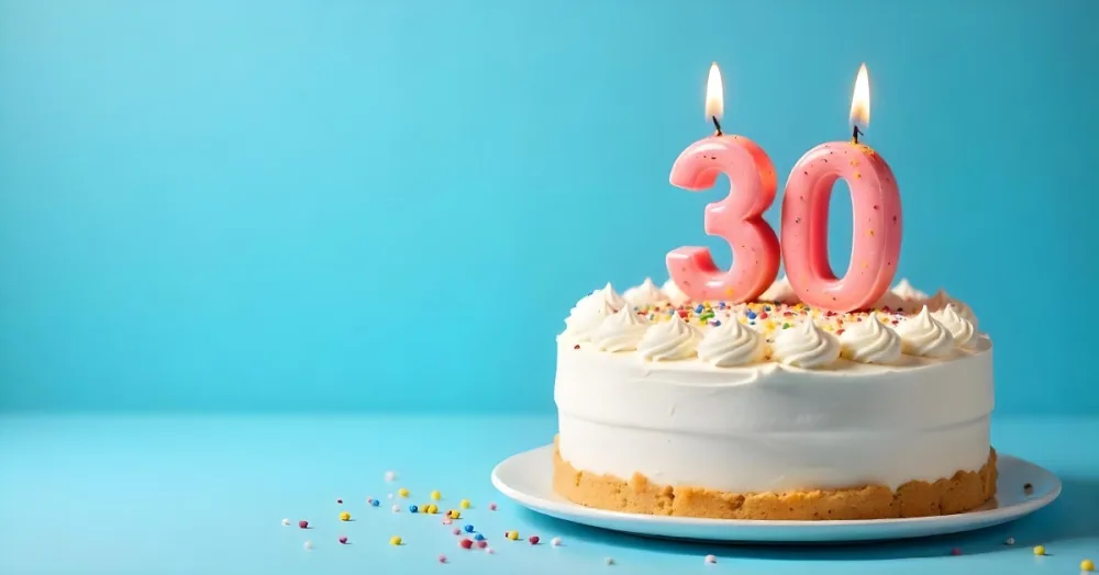 A 30th Birthday Cake With Candles On Top White Frosting And Sprinkles On A Blue Background 12 99ae