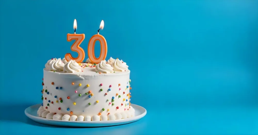 A 30th Birthday Cake With Candles On Top White Frosting And Sprinkles On A Blue Background 16 2322