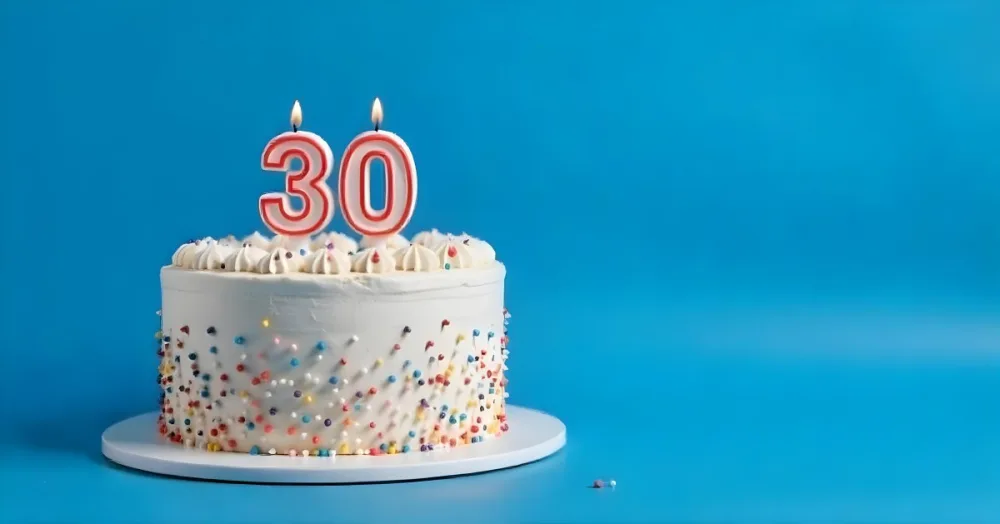 A 30th Birthday Cake With Candles On Top White Frosting And Sprinkles On A Blue Background 17 56c5
