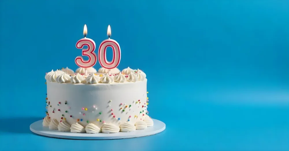 A 30th Birthday Cake With Candles On Top White Frosting And Sprinkles On A Blue Background 20 66e6