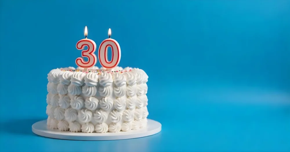 A 30th Birthday Cake With Candles On Top White Frosting And Sprinkles On A Blue Background 21 E7b7