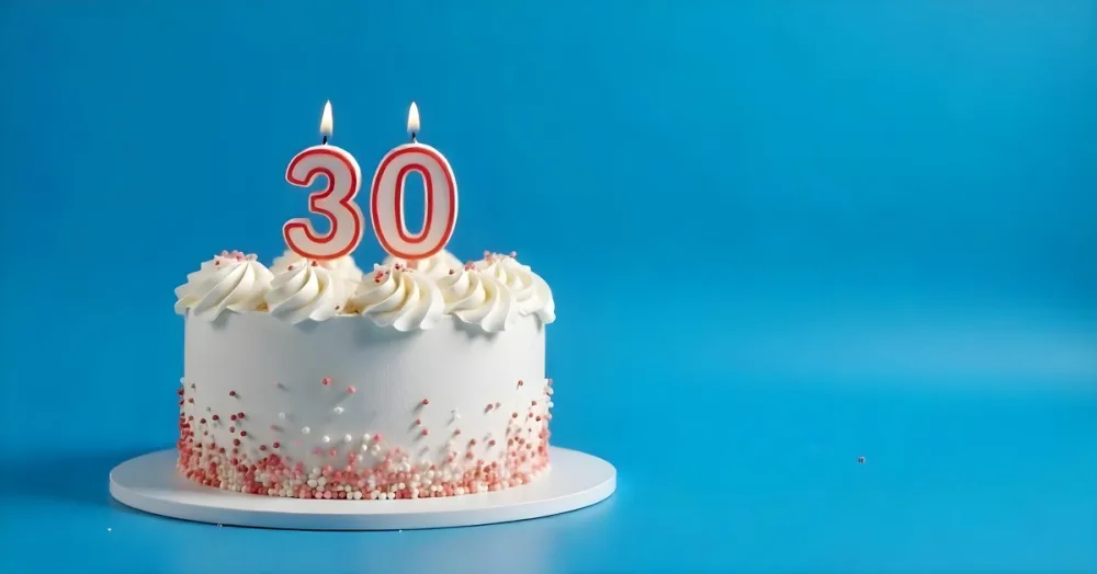 A 30th Birthday Cake With Candles On Top White Frosting And Sprinkles On A Blue Background 23 6826