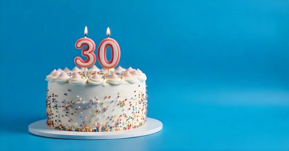 A 30th Birthday Cake With Candles On Top White Frosting And Sprinkles On A Blue Background 3 4403