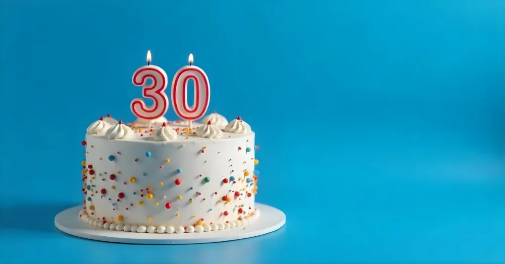 A 30th Birthday Cake With Candles On Top White Frosting And Sprinkles On A Blue Background 5 36f1
