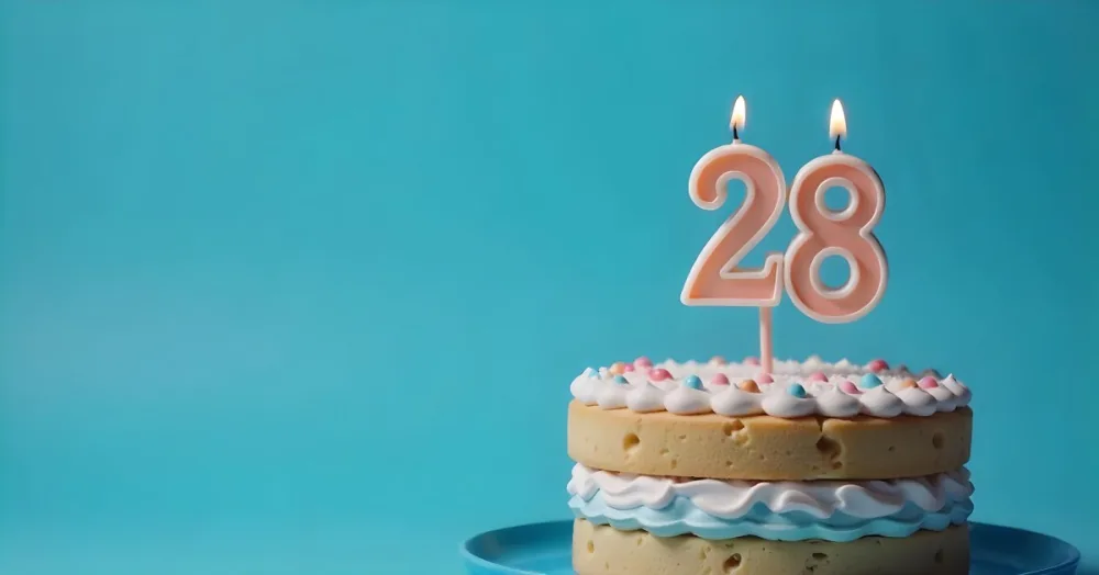 A Cake With Pink And Blue Frosting And A Candle With The Number 28 On A Blue Plate In A White Background 17 B705