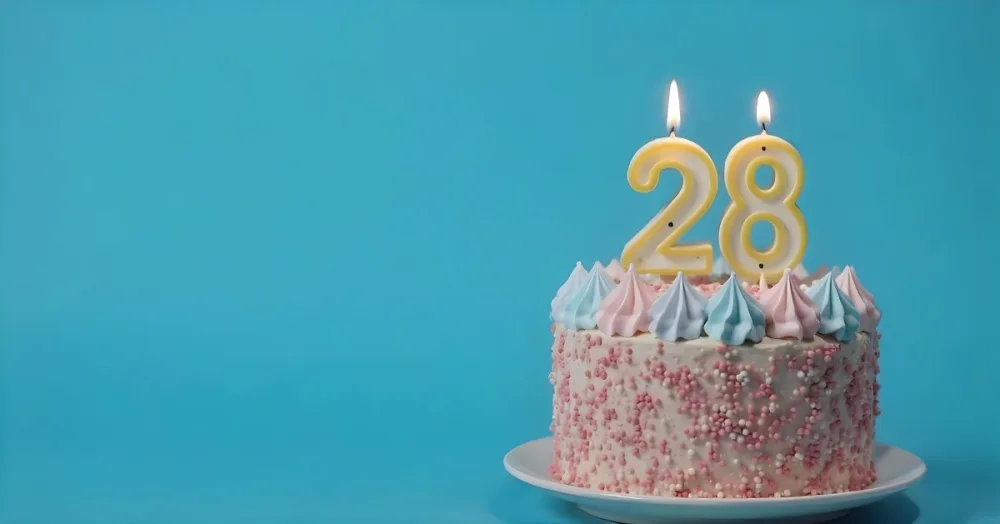 A Cake With Pink And Blue Frosting And A Candle With The Number 28 On A Blue Plate In A White Background 5 075d