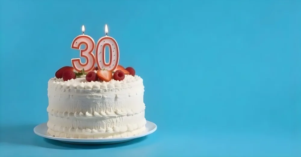 A Cake With Strawberries And Raspberries On Top With A Number 30 Candle On A Blue Background 1 24af
