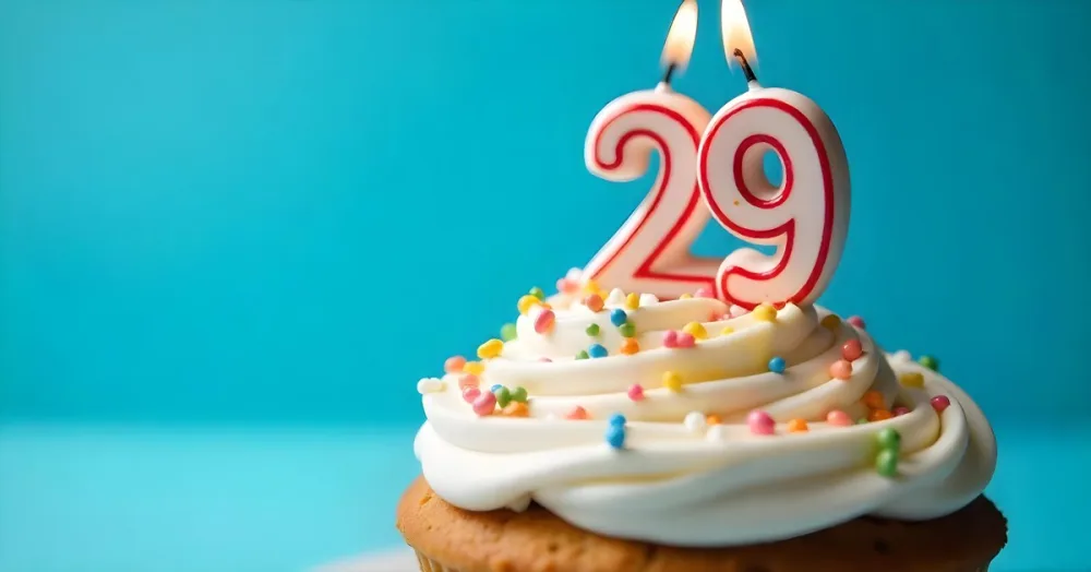 A Cake With White Frosting And Colorful Sprinkles Topped With A Candle In The Shape Of The Number 29 Blue Background 29 Fa75