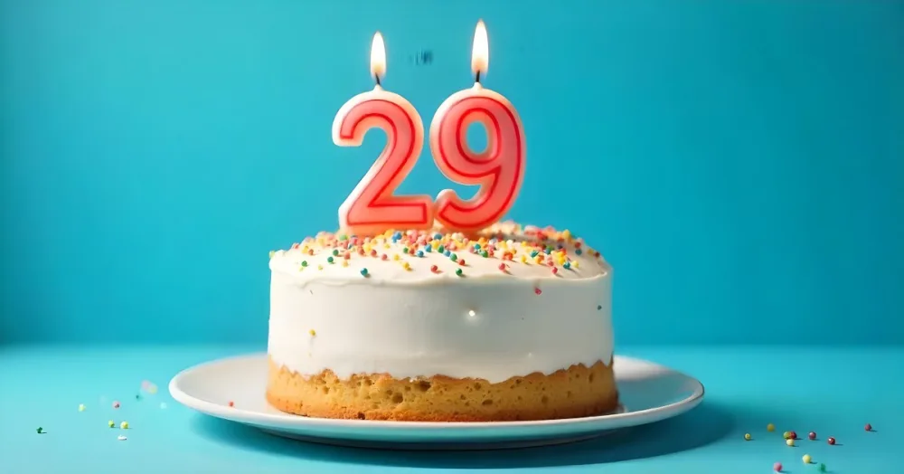 A Cake With White Frosting And Colorful Sprinkles Topped With A Candle In The Shape Of The Number 29 Blue Background 31 B6cb
