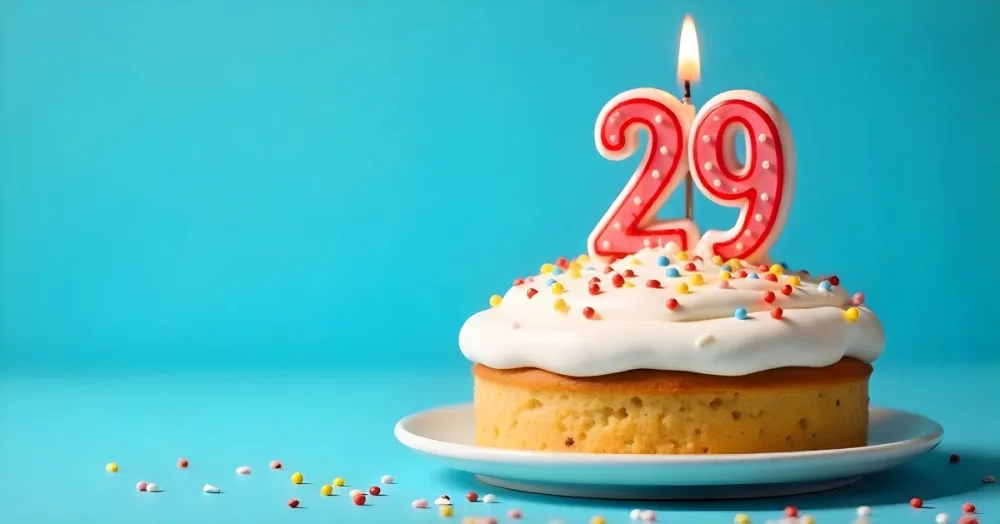 A Cake With White Frosting And Colorful Sprinkles Topped With A Candle In The Shape Of The Number 29 Blue Background 4 Ad2b