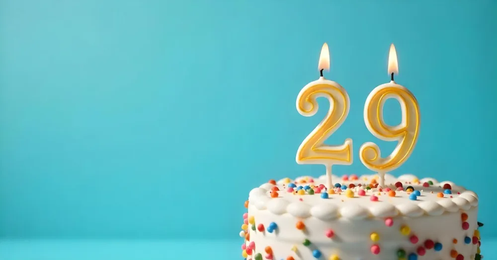 A Cake With White Frosting And Colorful Sprinkles Topped With A Candle In The Shape Of The Number 29 Blue Background 7 Dfe3