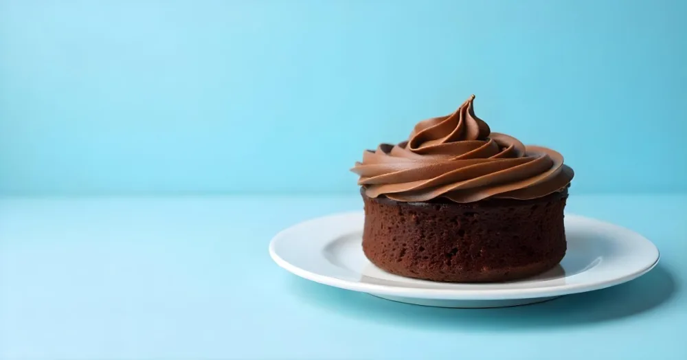 A Chocolate Cake With Chocolate Frosting On A White Plate Plain Blue Background Studio Shot Minimalist Food Photography 17 0b5a