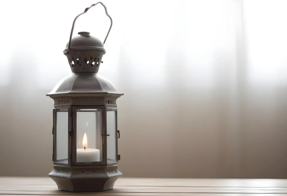 An Antique Metal Lantern With Glass Panels Sits On A Glass Surface A Candle Burning Inside Against A Blurred White Background 31 3082