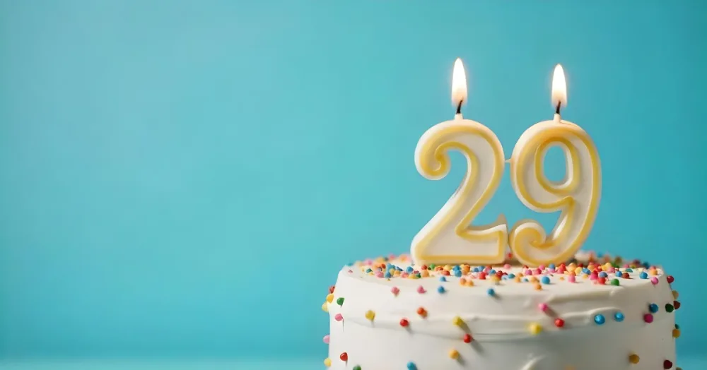 Birthday Cake With White Frosting And Colorful Sprinkles A Candle In The Shape Of The Number 29 Light Blue Background 16 6f06