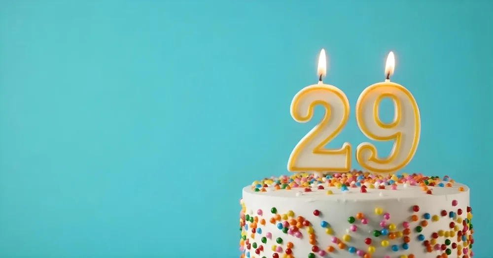 Birthday Cake With White Frosting And Colorful Sprinkles A Candle In The Shape Of The Number 29 Light Blue Background 20 0883