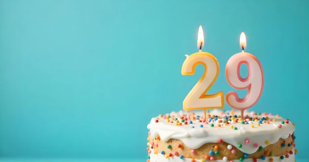 Birthday Cake With White Frosting And Colorful Sprinkles A Candle In The Shape Of The Number 29 Light Blue Background 26 Ade5