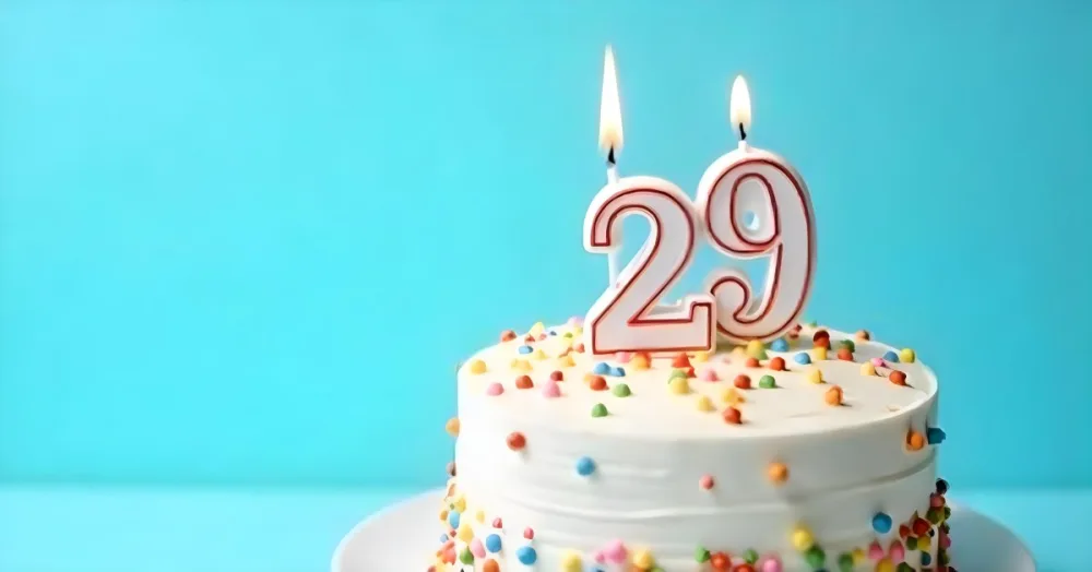 Birthday Cake With White Frosting And Colorful Sprinkles A Candle In The Shape Of The Number 29 Light Blue Background 3 529d