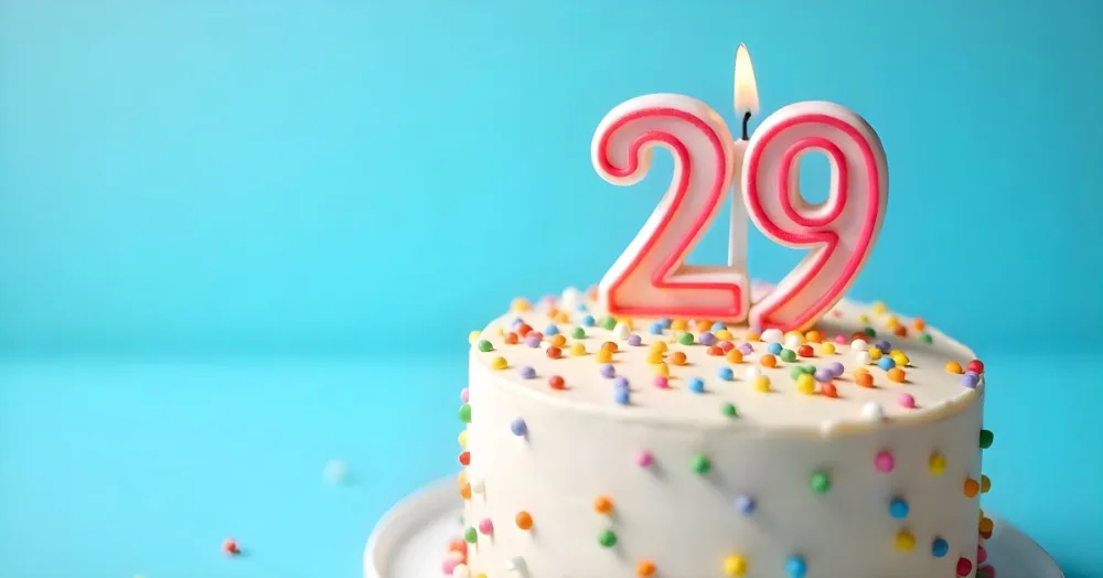 Birthday Cake With White Frosting And Colorful Sprinkles A Candle In The Shape Of The Number 29 Light Blue Background 9 26d9