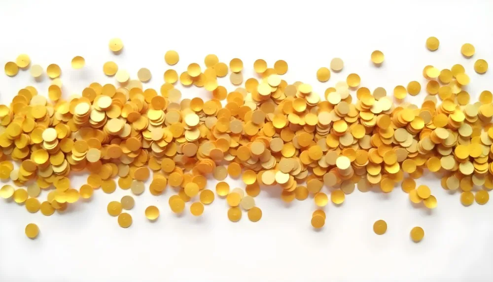 Golden Confetti Scattered On A White Surface Creating A Textured And Shimmering Effect Ideal For Festive Backgrounds Or Celebratory Designs With A Clean And Minimalist Aesthetic 40 E299