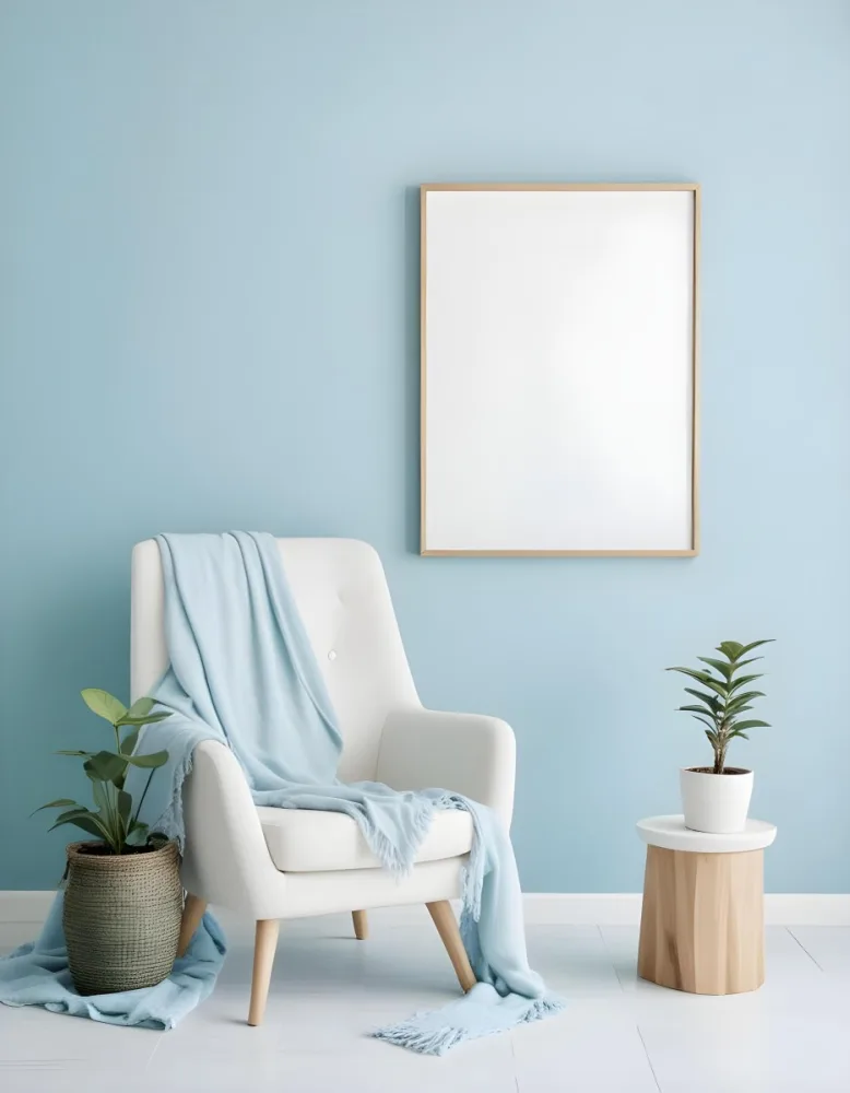 A White Armchair With A Blue Blanket Draped Over It A Small Side Table With A Potted Plant And A Blank White Frame On A Green Wall 16 C8d1