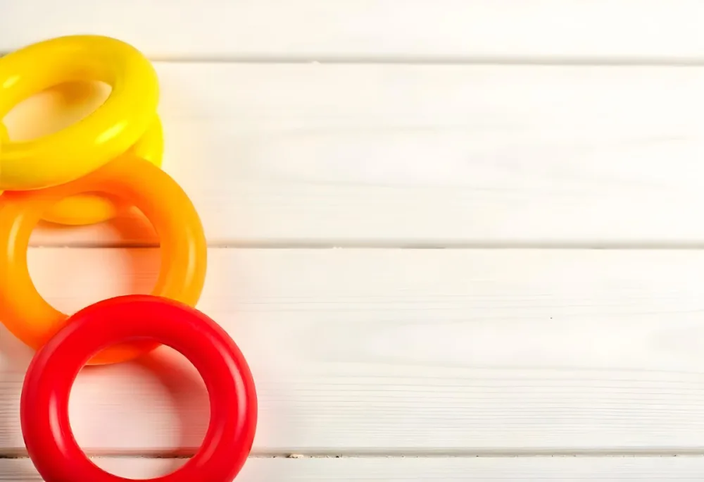 A Red Yellow And Orange Stacking Ring Toy On A White Wooden Surface The Rings Are Plastic And Shiny Close Up Shot 19 71a9