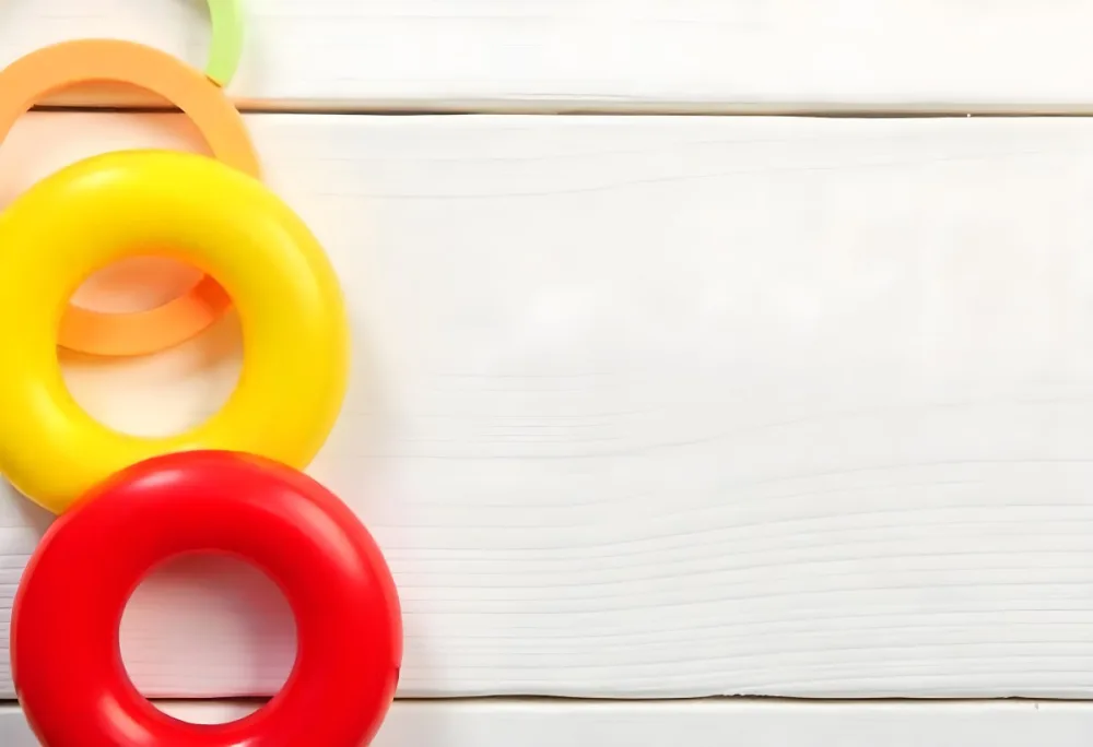 A Red Yellow And Orange Stacking Ring Toy On A White Wooden Surface The Rings Are Plastic And Shiny Close Up Shot 21 4da4