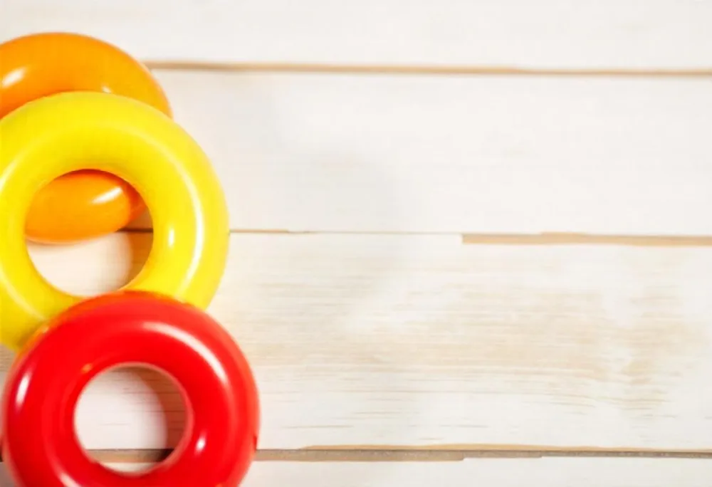A Red Yellow And Orange Stacking Ring Toy On A White Wooden Surface The Rings Are Plastic And Shiny Close Up Shot 31 744b
