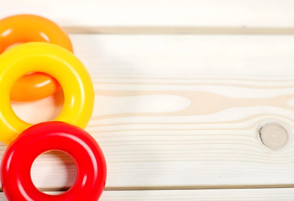 A Red Yellow And Orange Stacking Ring Toy On A White Wooden Surface The Rings Are Plastic And Shiny Close Up Shot 45 7ce1