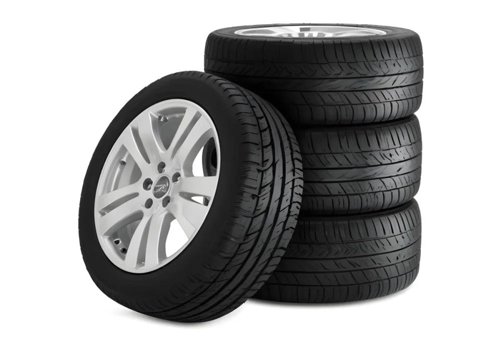 A Stack Of Four Black Tires With Black Rims One Tire Is Leaning Against The Stack The Background Is Black 3 312d