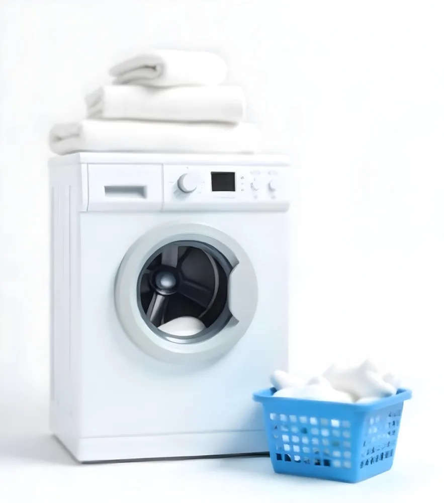 A White Washing Machine With Three White Pillows And Three Towels On Top A Blue Basket With White Clothes On A White Background 61 1cf3