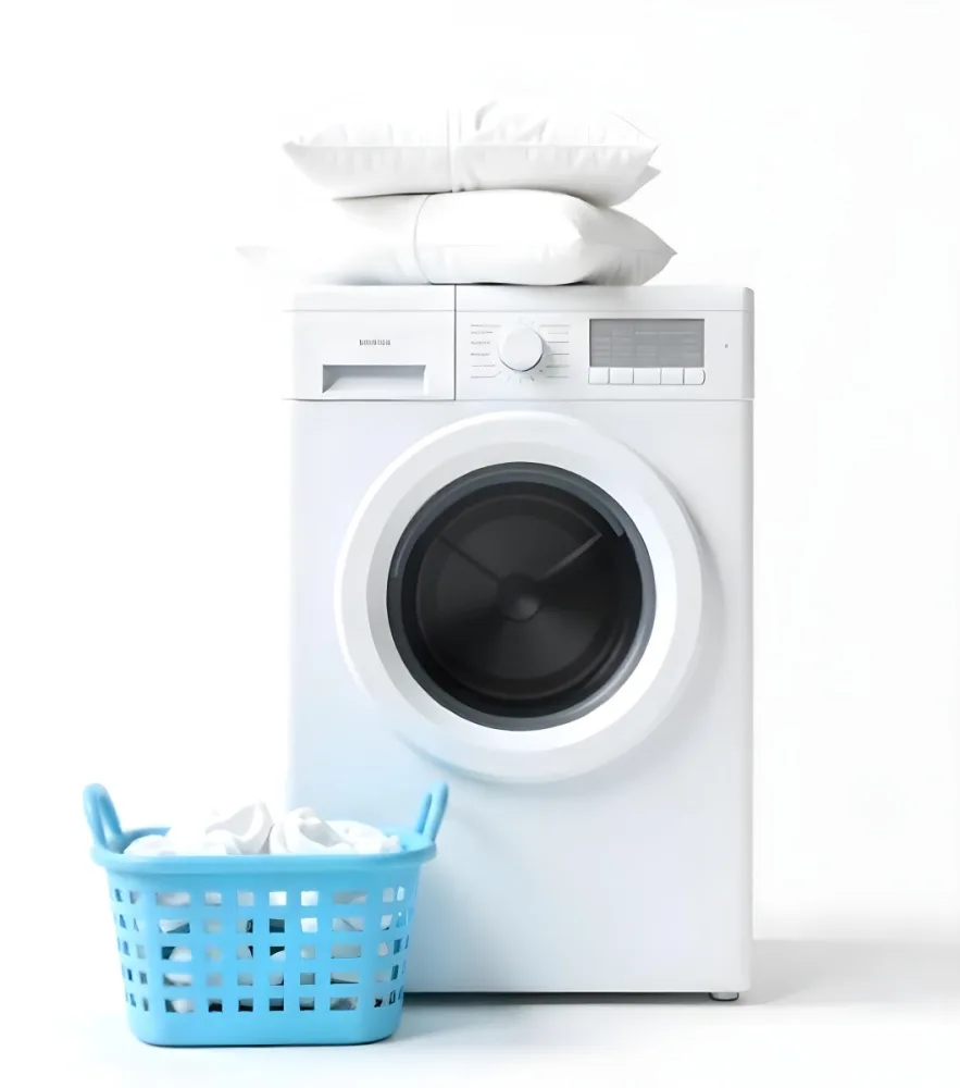 A White Washing Machine With Three White Pillows And Three Towels On Top A Blue Basket With White Clothes On A White Background 63 273f