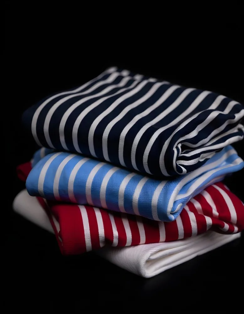 Stack Of Folded Shirts With Vertical Stripes In Black Blue Red And White Colors On A Black Surface 6 2dca