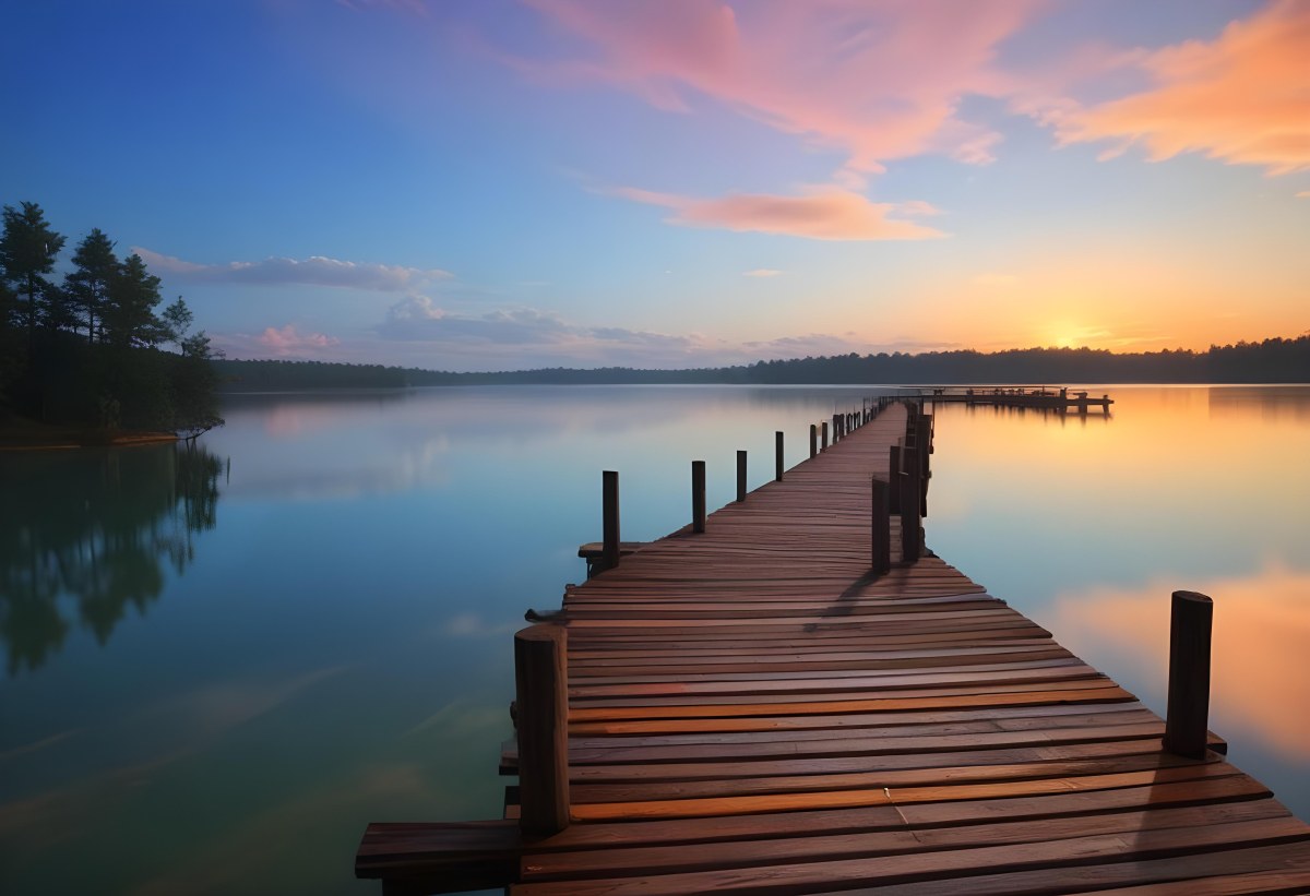 A Wooden Pier Stretches Out Into A Calm Lake The Sky Is A Mix Of Blue Orange And Pink Reflecting On The Water Trees Line The Shore In The Background 22 Ff56