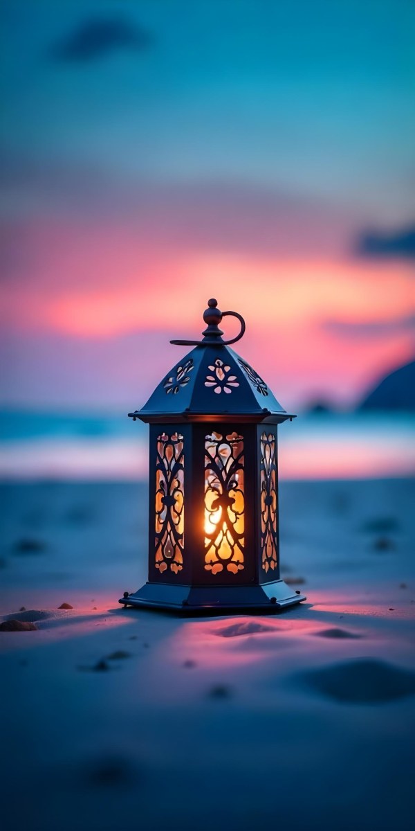 A Black Metal Lantern With Intricate Cutouts Glowing With Warm Light Sits On A Sandy Beach With A Vibrant Pink And Blue Sunset Sky 5 Bcd8