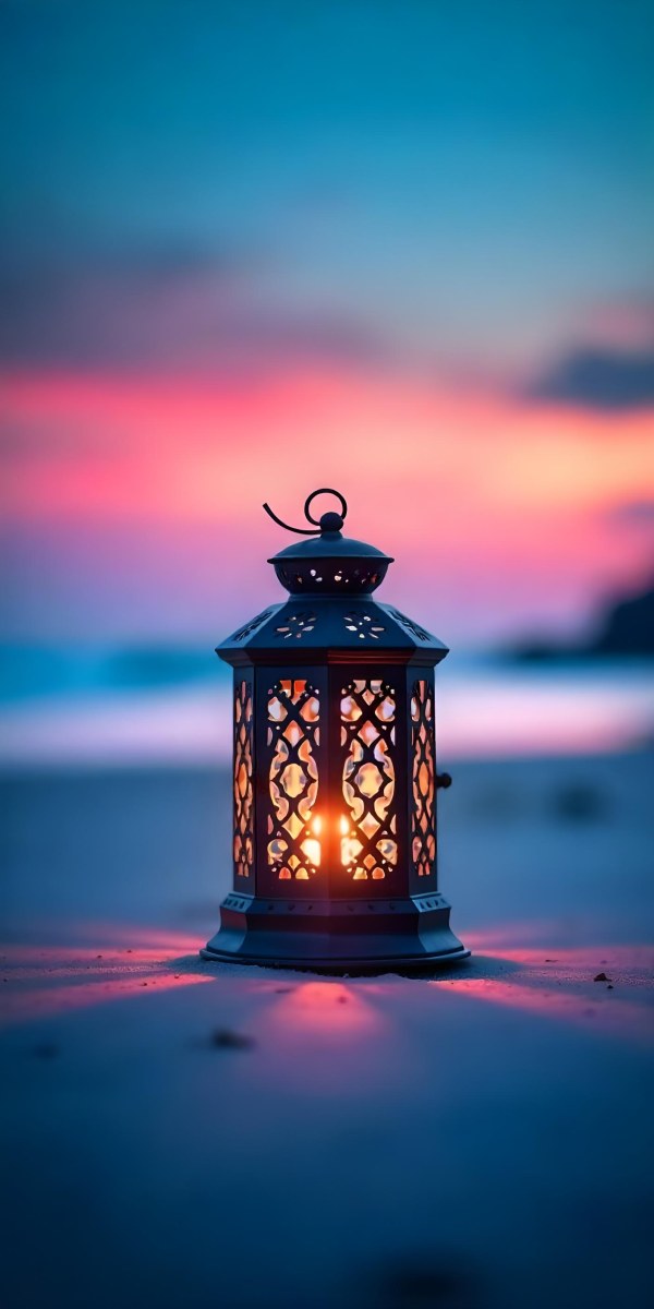 A Black Metal Lantern With Intricate Cutouts Glowing With Warm Light Sits On A Sandy Beach With A Vibrant Pink And Blue Sunset Sky 7 E22e