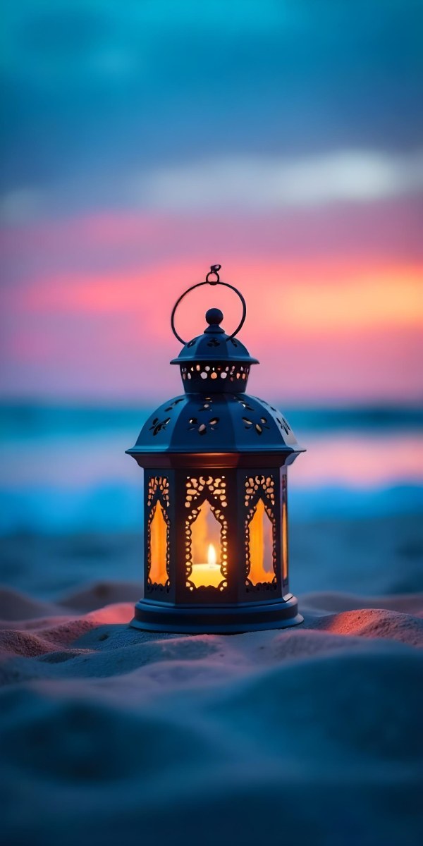 A Black Metal Lantern With Intricate Cutouts Glowing With Warm Light Sits On A Sandy Beach With A Vibrant Pink And Blue Sunset Sky 8 Ecbf