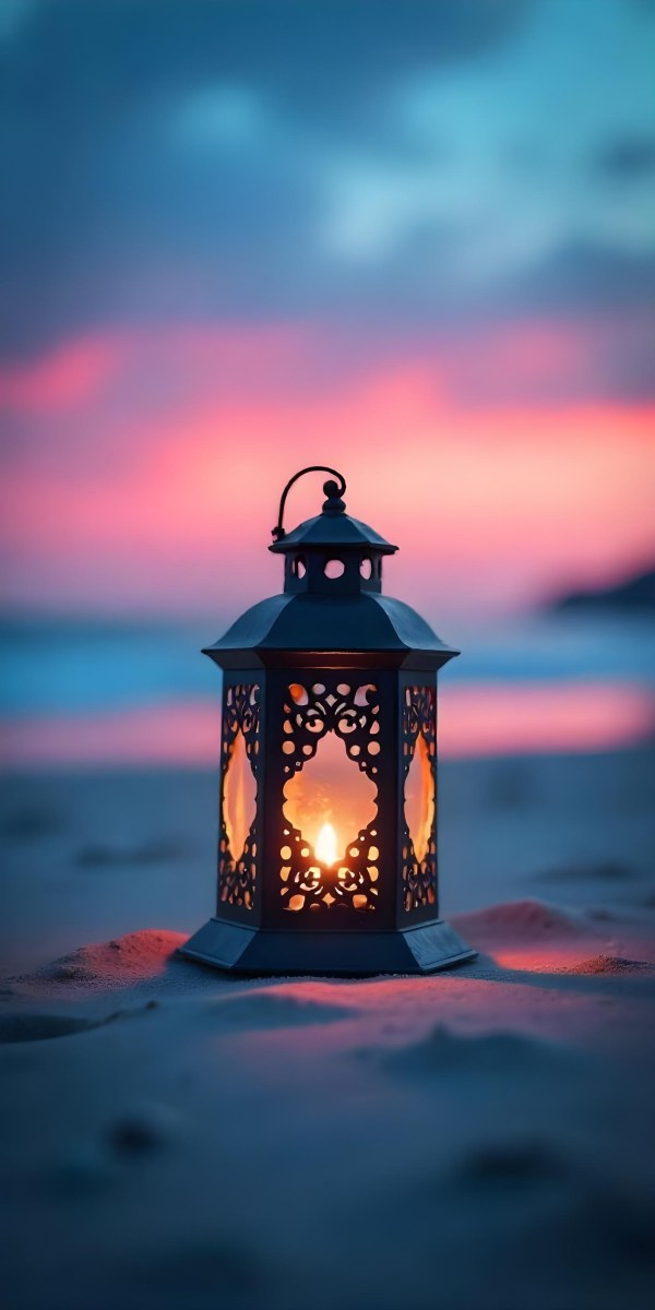 A Black Metal Lantern With Intricate Cutouts Glowing With Warm Light Sits On A Sandy Beach With A Vibrant Pink And Blue Sunset Sky 9 4de0