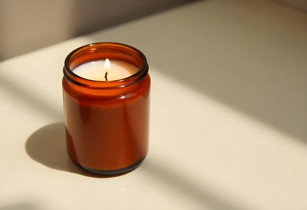 A Brown Glass Jar Candle With A Flickering Flame Casting Soft Shadows On A Neutral Surface Minimalist Aesthetic Warm Lighting Simple Composition Cozy Atmosphere 23 25f2