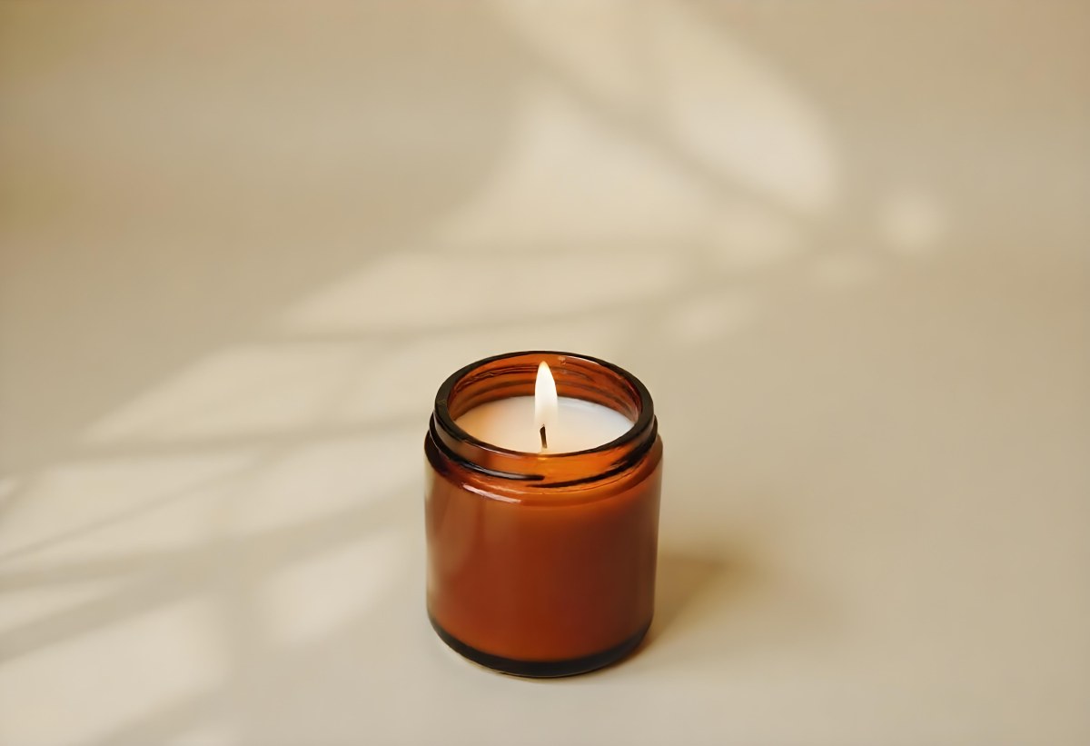 A Brown Glass Jar Candle With A Flickering Flame Casting Soft Shadows On A Neutral Surface Minimalist Aesthetic Warm Lighting Simple Composition Cozy Atmosphere 8 3005