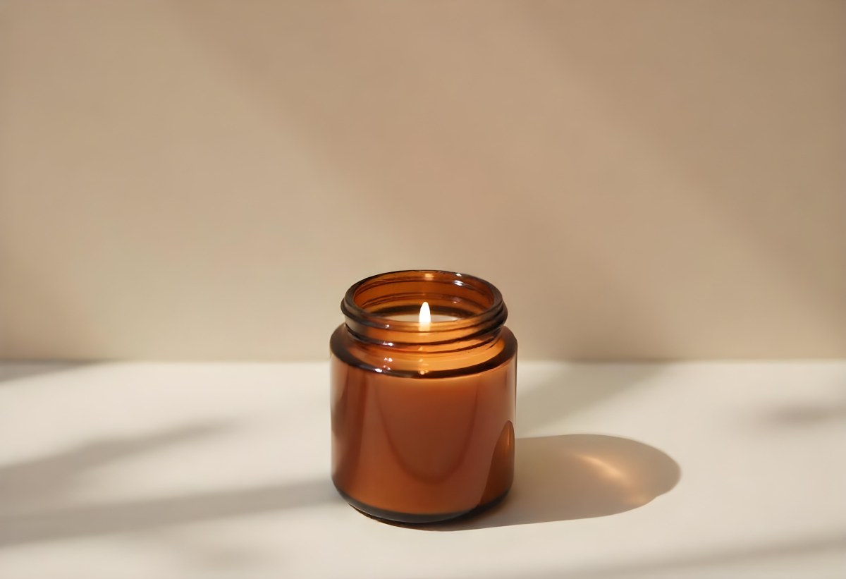 A Brown Glass Jar Candle With A Flickering Flame Casting Soft Shadows On A Neutral Surface Minimalist Aesthetic Warm Lighting Simple Composition Cozy Atmosphere 9 F56f