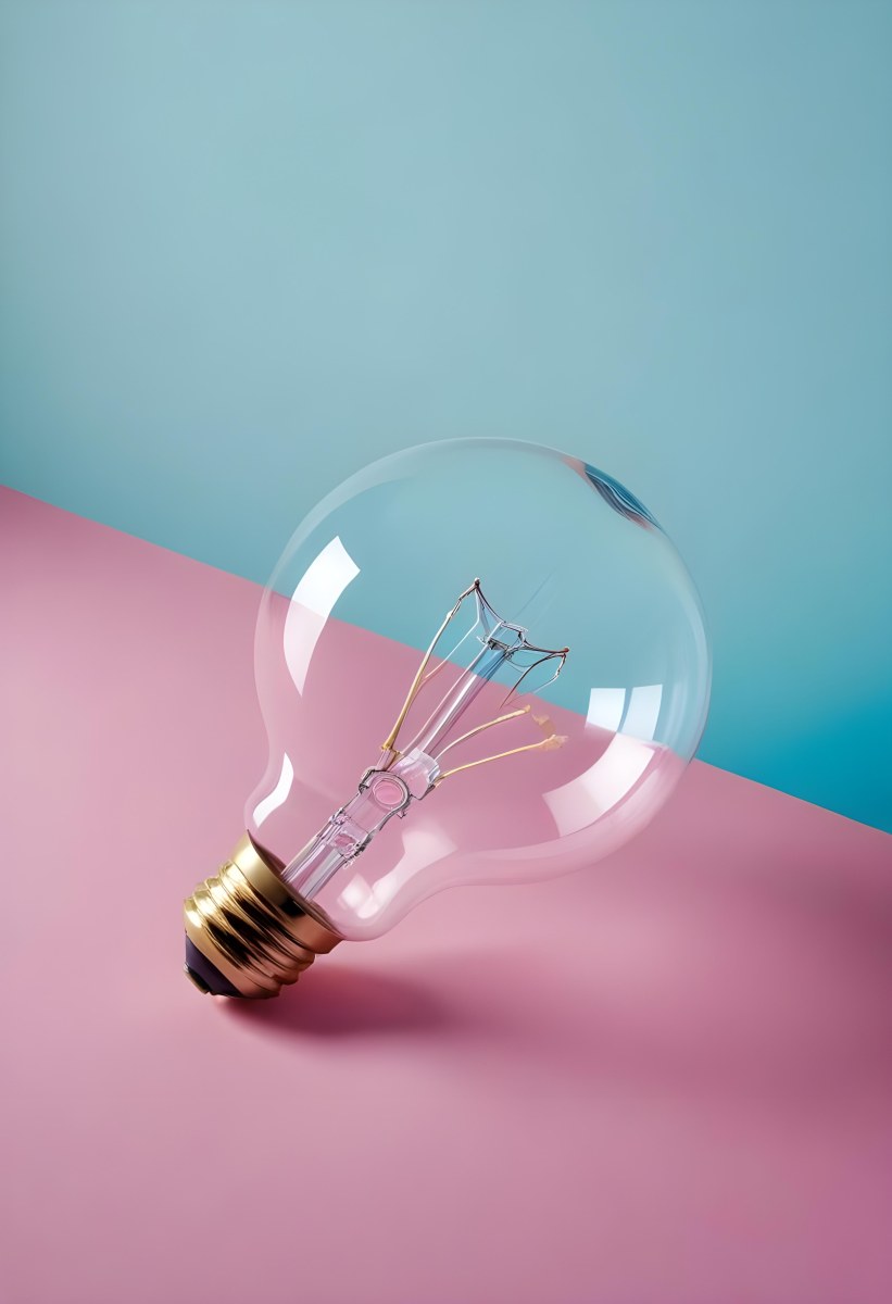 A Clear Light Bulb Lying On A Pink Surface With A Blue Background The Bulb Has A Classic Filament Design Visible Inside The Color Contrast Between The Pink And Blue Creates A Vibrant Aesthetic 21 Cae1